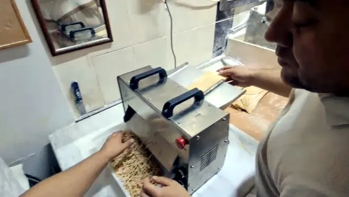 Makinenin ön tarafından kesilmiş erişte şeritleri dökülürken